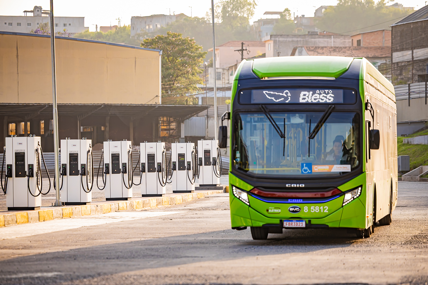 Frota de ônibus da Auto Bless em fila, com prédios ao fundo
